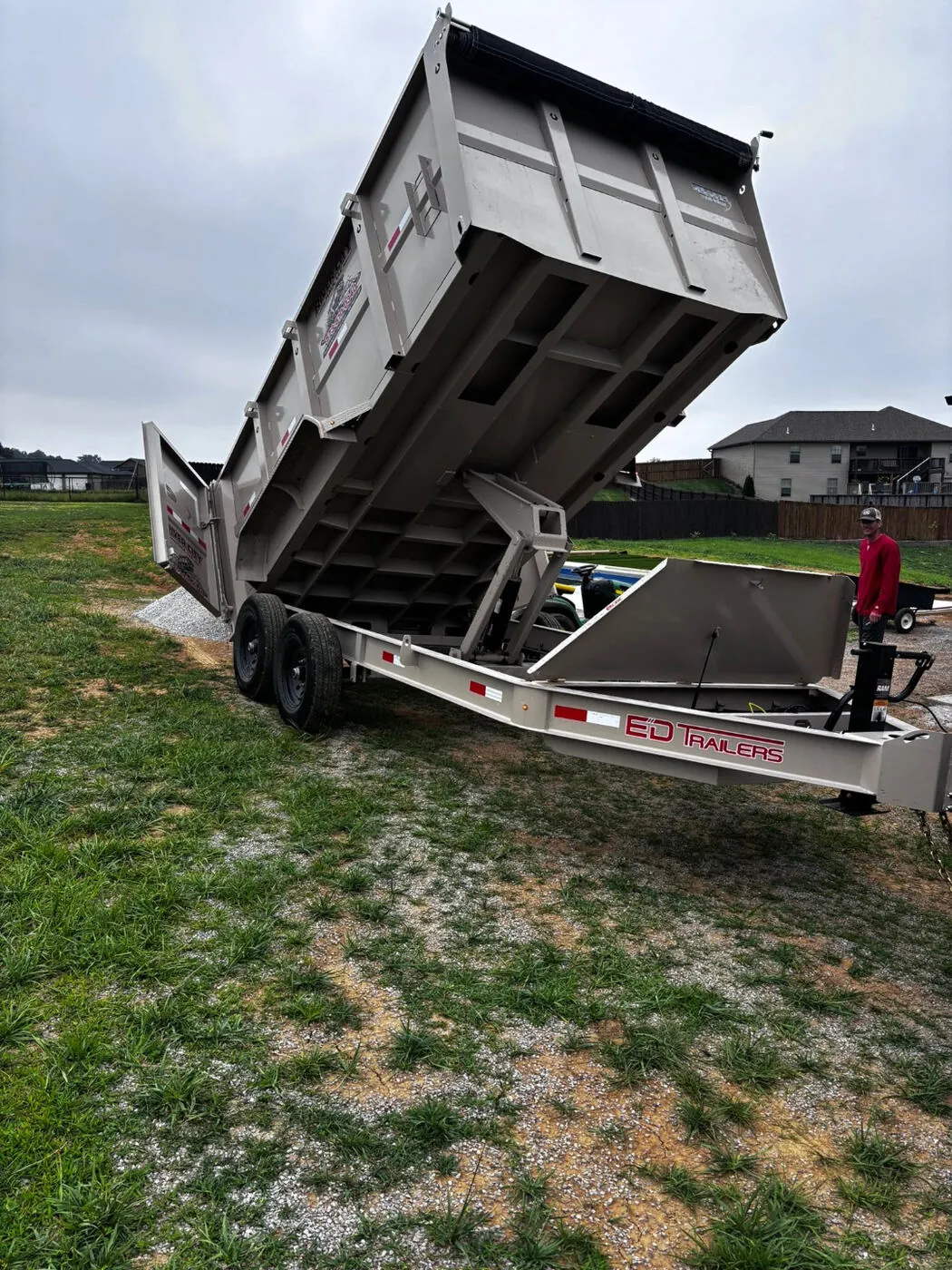Heavy-duty E-D Trailers dump trailer raised, ready to offload material in an open yard.