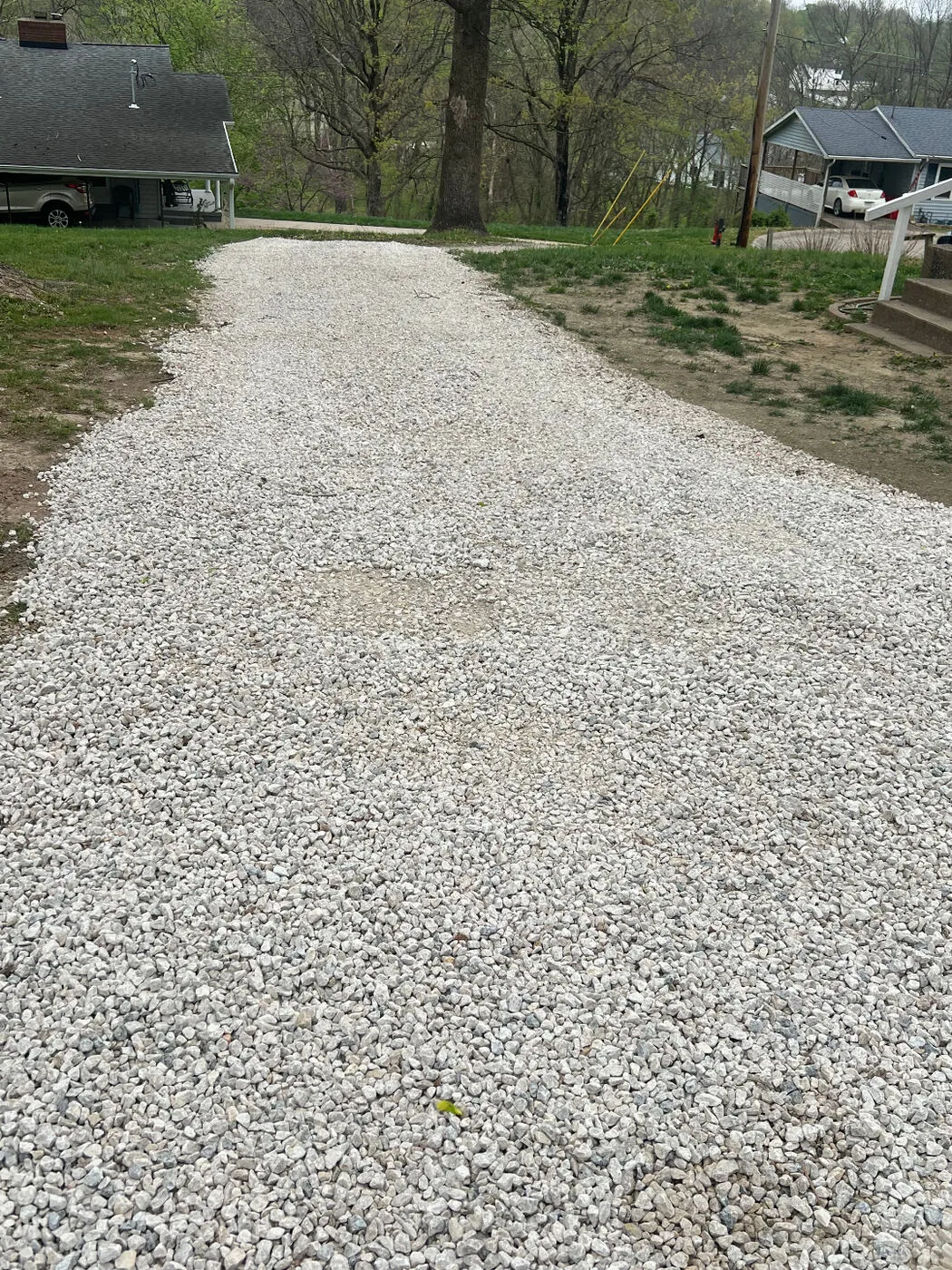 New gravel driveway freshly spread and graded between two homes.
